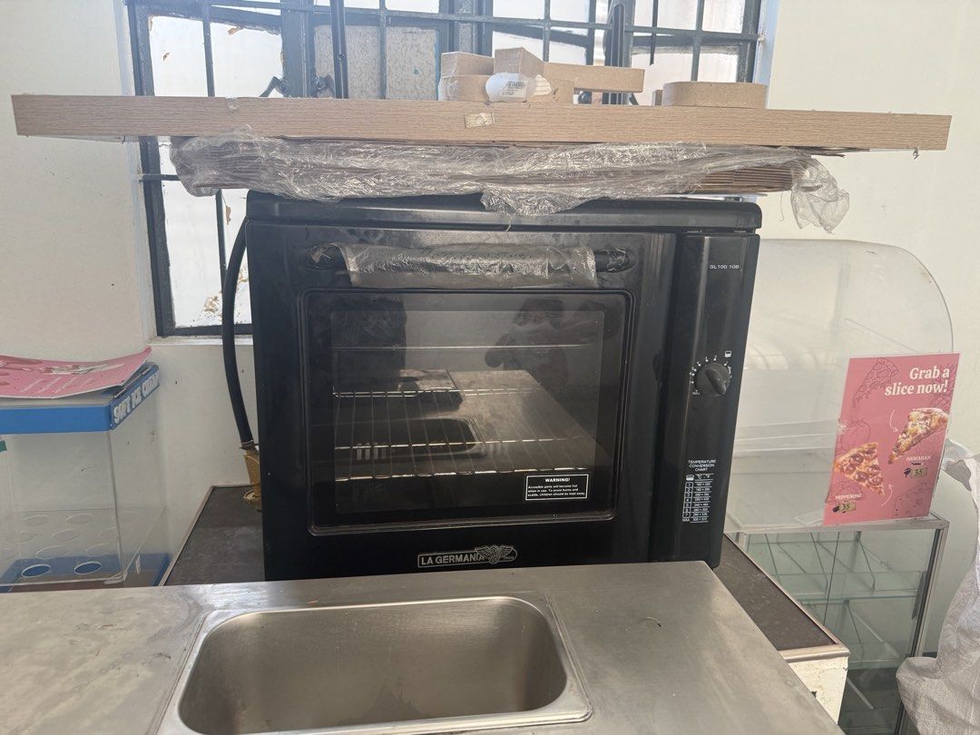 La Germania SL100 10B Black Oven (Category: Ovens & Toasters) located in Imus. Submitted by neirasalonga_ (Listing ID 1470441420, Image 1). Description: - Brand: La Germania - Model: SL100 10B - Color: Sleek black with glass door and metal handle - Controls: Rotary temperature knob with built-in conversion chart - Interior: Clean condition with wire rack and side baking tray supports - Condition: Ready for kitchen use.