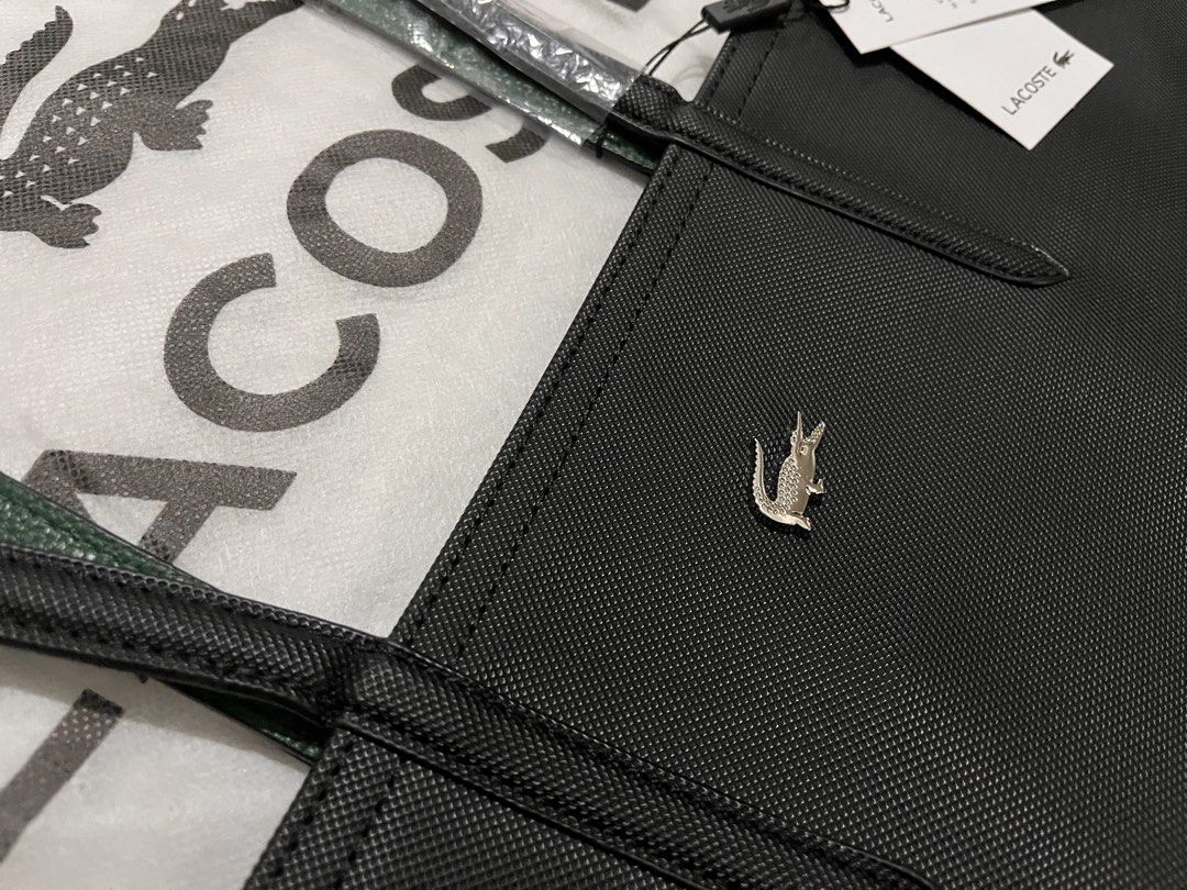 Lacoste Black Tote Bag (Category: Tote Bags) located in Quezon City. Submitted by pickleballpaddle (Listing ID 1470528705, Image 2). Description: - Brand: Lacoste - Color: Classic Black - Material: Durable textured PVC - Design: Structured handles with a centered silver metal crocodile logo - Condition: Brand new with original retail tags attached - Protection: Straps still wrapped in protective plastic - Cleanliness: 100% clean interior and exte