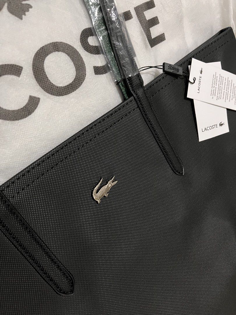 Lacoste Black Tote Bag (Category: Tote Bags) located in Quezon City. Submitted by pickleballpaddle (Listing ID 1470528705, Image 3). Description: - Brand: Lacoste - Color: Classic Black - Material: Durable textured PVC - Design: Structured handles with a centered silver metal crocodile logo - Condition: Brand new with original retail tags attached - Protection: Straps still wrapped in protective plastic - Cleanliness: 100% clean interior and exte