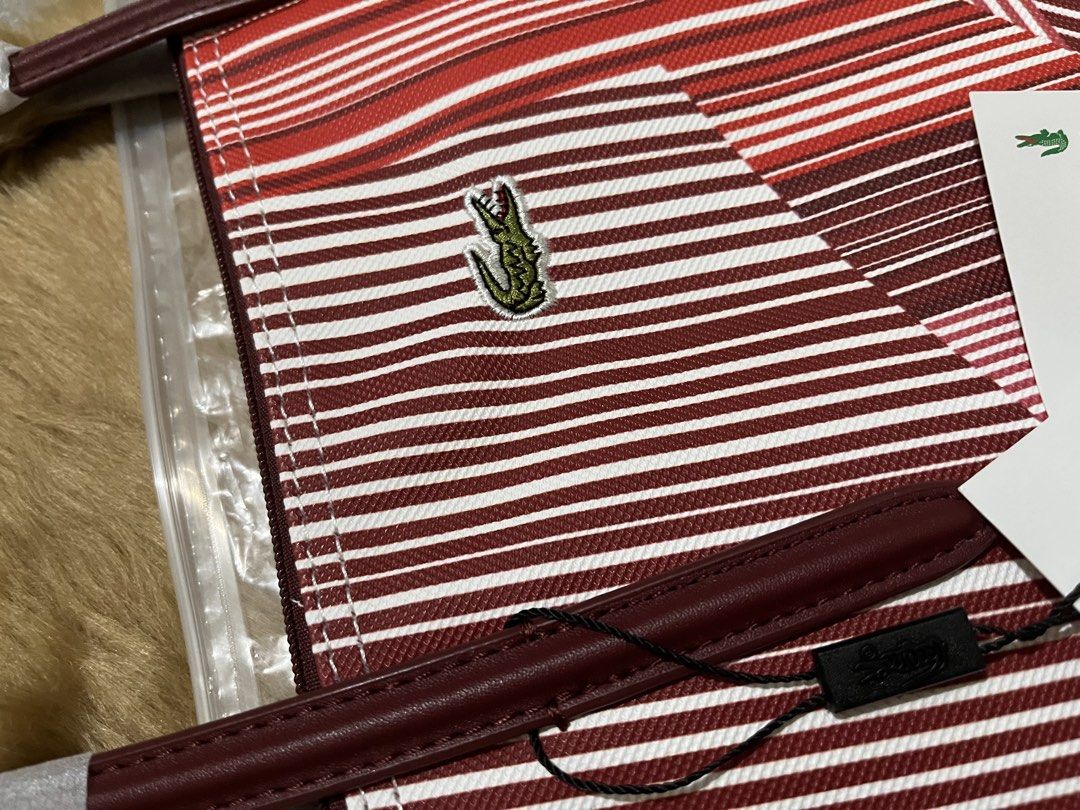 Lacoste geometric red and white striped tote bag (Category: Tote Bags) located in Quezon City. Submitted by pickleballpaddle (Listing ID 1470527607, Image 2). Description: - Brand new with original tags still attached - Stylish geometric stripe design in red, white, and burgundy - Signature embroidered green crocodile logo on the front - Durable burgundy leather handles and matching zipper pull tab - Clean white interior lining with a convenient 