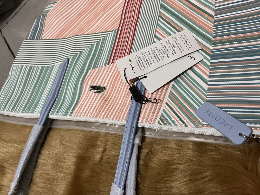 Lacoste Multicolored Striped Tote Bag (Category: Tote Bags) located in Quezon City. Submitted by pickleballpaddle (Listing ID 1470329228, Image 2). Description: - Brand new, unused Lacoste tote bag with original tags attached - Eye-catching striped geometric pattern in green, pink, and white - Light blue shoulder straps still wrapped in protective plastic - Secure top zipper closure with a matching light blue pull tab - Spacious interior designed