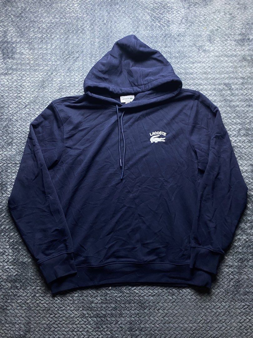 Lacoste Navy Blue Regular Fit Hoodie (Category: Coats, Jackets and Outerwear) located in Olongapo. Submitted by WAVYT (Listing ID 1470552411, Image 1). Description: - Brand: Lacoste - Color: Navy Blue - Size: US XL / French Size 6 (Regular Fit) - Design: Large white embroidered Lacoste text and crocodile logo on the chest - Details: Classic drawstring hood with metal tips, extra small embroidered croc near the bottom hem, and 'French Sportswear e