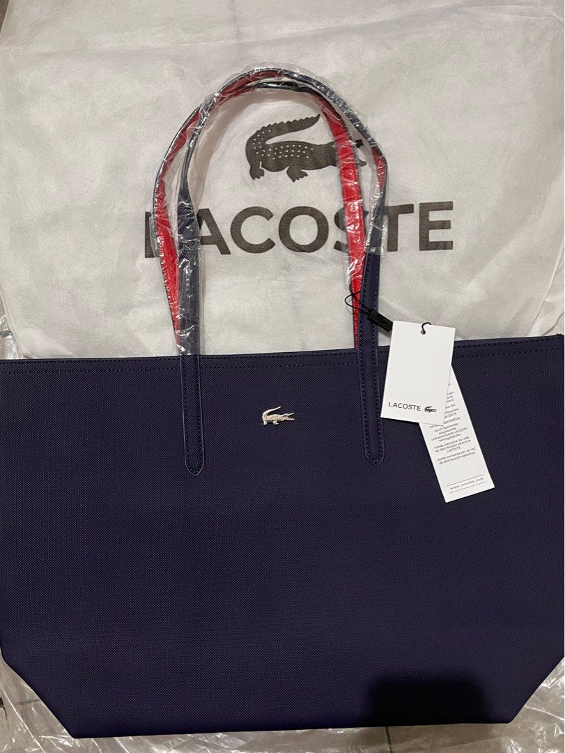 Lacoste Navy Blue Tote Bag with Red Interior (Category: Tote Bags) located in Quezon City. Submitted by pickleballpaddle (Listing ID 1470529043, Image 1). Description: - Brand: Lacoste - Color: Navy blue exterior with striking bright red interior - Material: Textured exterior with silver crocodile logo badge - Condition: Brand new, handles still wrapped in protective plastic, original store tags attached - Inclusion: Comes with a matching white L