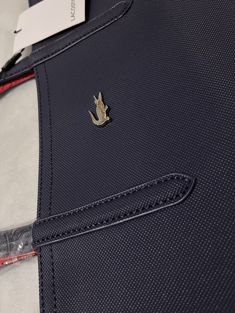 Lacoste Navy Blue Tote Bag with Red Interior (Category: Tote Bags) located in Quezon City. Submitted by pickleballpaddle (Listing ID 1470529043, Image 3). Description: - Brand: Lacoste - Color: Navy blue exterior with striking bright red interior - Material: Textured exterior with silver crocodile logo badge - Condition: Brand new, handles still wrapped in protective plastic, original store tags attached - Inclusion: Comes with a matching white L