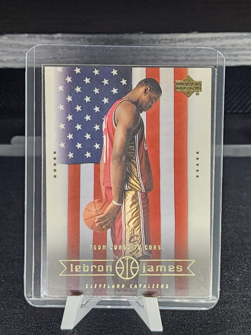 LeBron James (Category: Raw Singles) located in Manila. Submitted by kg613 (Listing ID 1470380107, Image 1). Description: - Item: 2003 LeBron James Upper Deck Basketball Card - Front Design: LeBron James with an iconic American flag background - Back Design: Senior high school stats, player bio, small portrait, Upper Deck, and Cleveland Cavaliers logos - Condition: Protected and stored inside a top loader case - Ideal for: Basketball fans, sports
