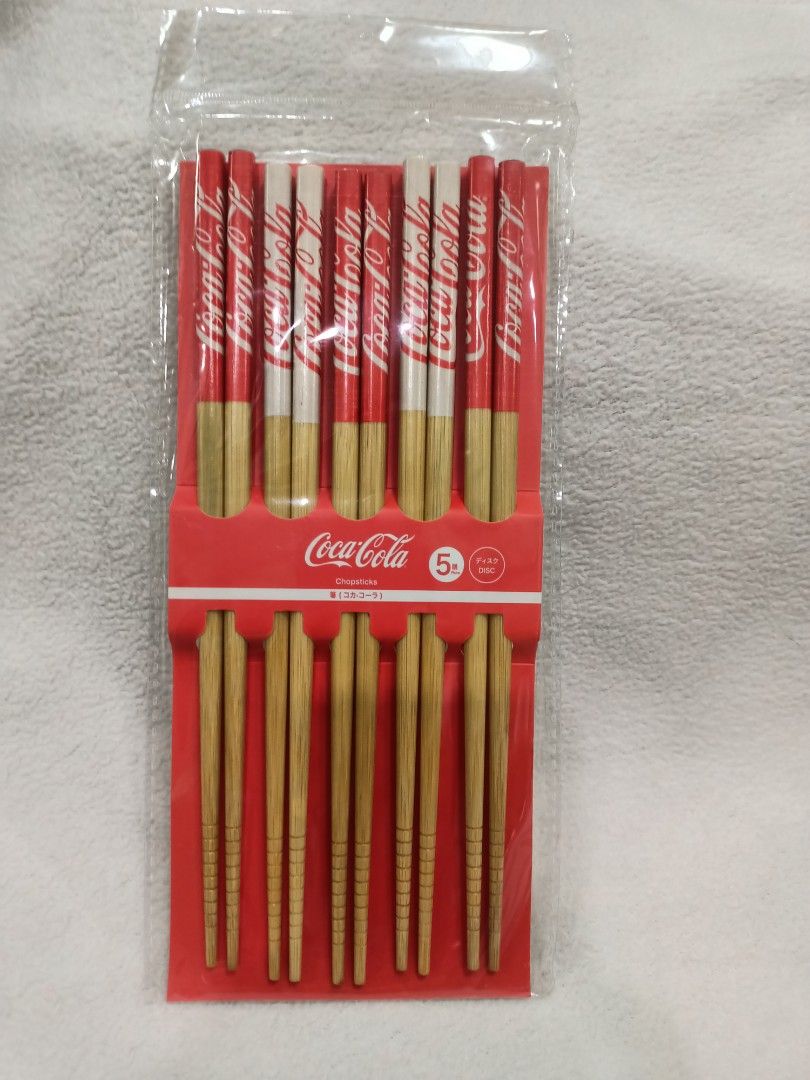 Licensed Coca-Cola Chopsticks Plastic Storage Jar Coaster Merchandise Bundle Set (Category: Food Organization & Storage) located in Manila. Submitted by jollynest24 (Listing ID 1470504579, Image 2). Description: - Official 2022 Coca-Cola Collector's bundle - 2x packs of wooden chopsticks (5 pairs per pack, unopened) - 1x clear plastic storage jar with red Coca-Cola logo, 'What You Want Is A Coke' text, and red lid - 1x round wooden coaster stampe