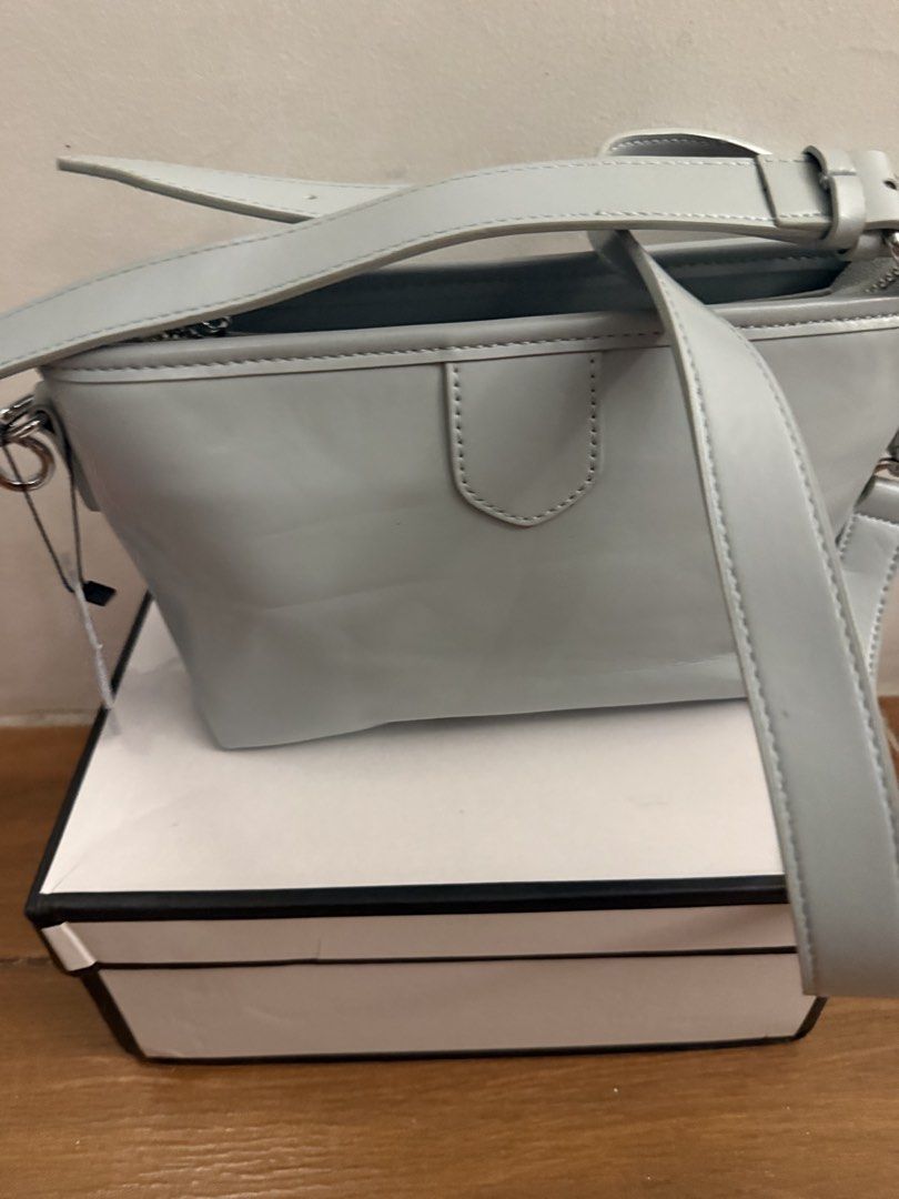 Light blue cross-body handbag with bear tag (Category: Cross-body Bags) located in Bulacan. Submitted by emjay_17 (Listing ID 1470452289, Image 2). Description: - Color: Light blue - Material: Sleek leather-like texture - Closure: Secure top zipper with clean interior lining - Strap: Includes matching adjustable shoulder strap - Extras: Cute bear-shaped charm included - Condition: Kept in shape with original stuffing inside - Packaging: Box inclu