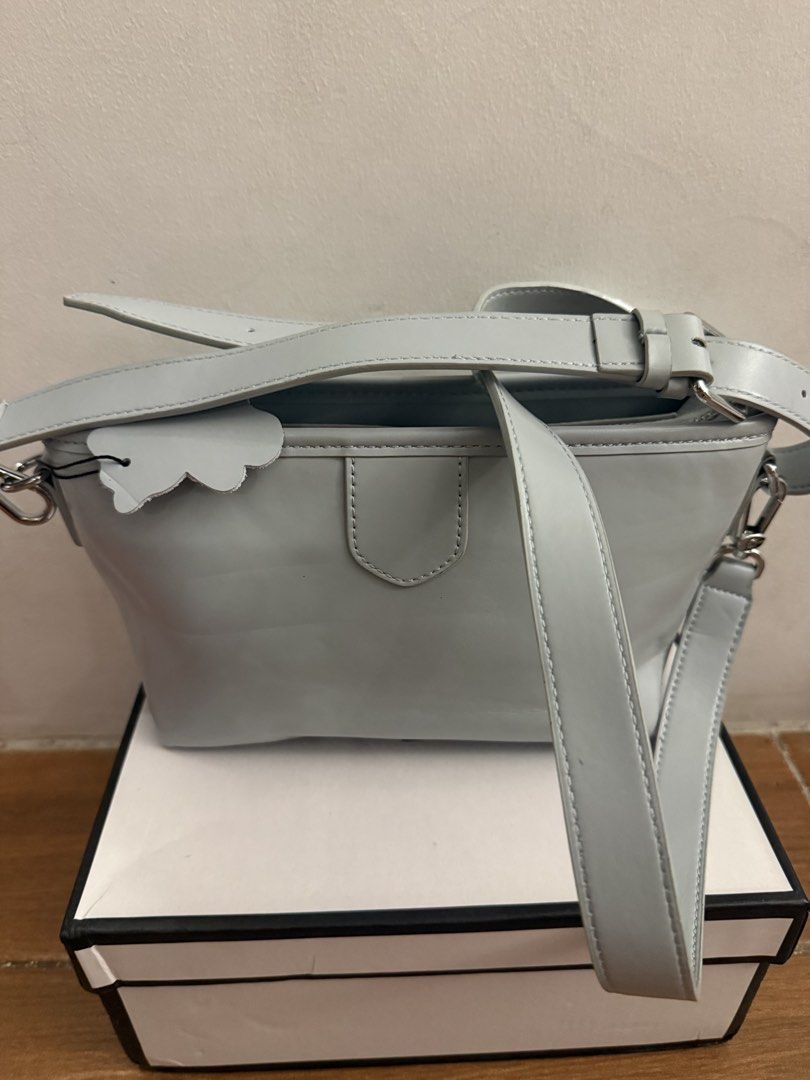 Light blue cross-body handbag with bear tag (Category: Cross-body Bags) located in Bulacan. Submitted by emjay_17 (Listing ID 1470452289, Image 1). Description: - Color: Light blue - Material: Sleek leather-like texture - Closure: Secure top zipper with clean interior lining - Strap: Includes matching adjustable shoulder strap - Extras: Cute bear-shaped charm included - Condition: Kept in shape with original stuffing inside - Packaging: Box inclu