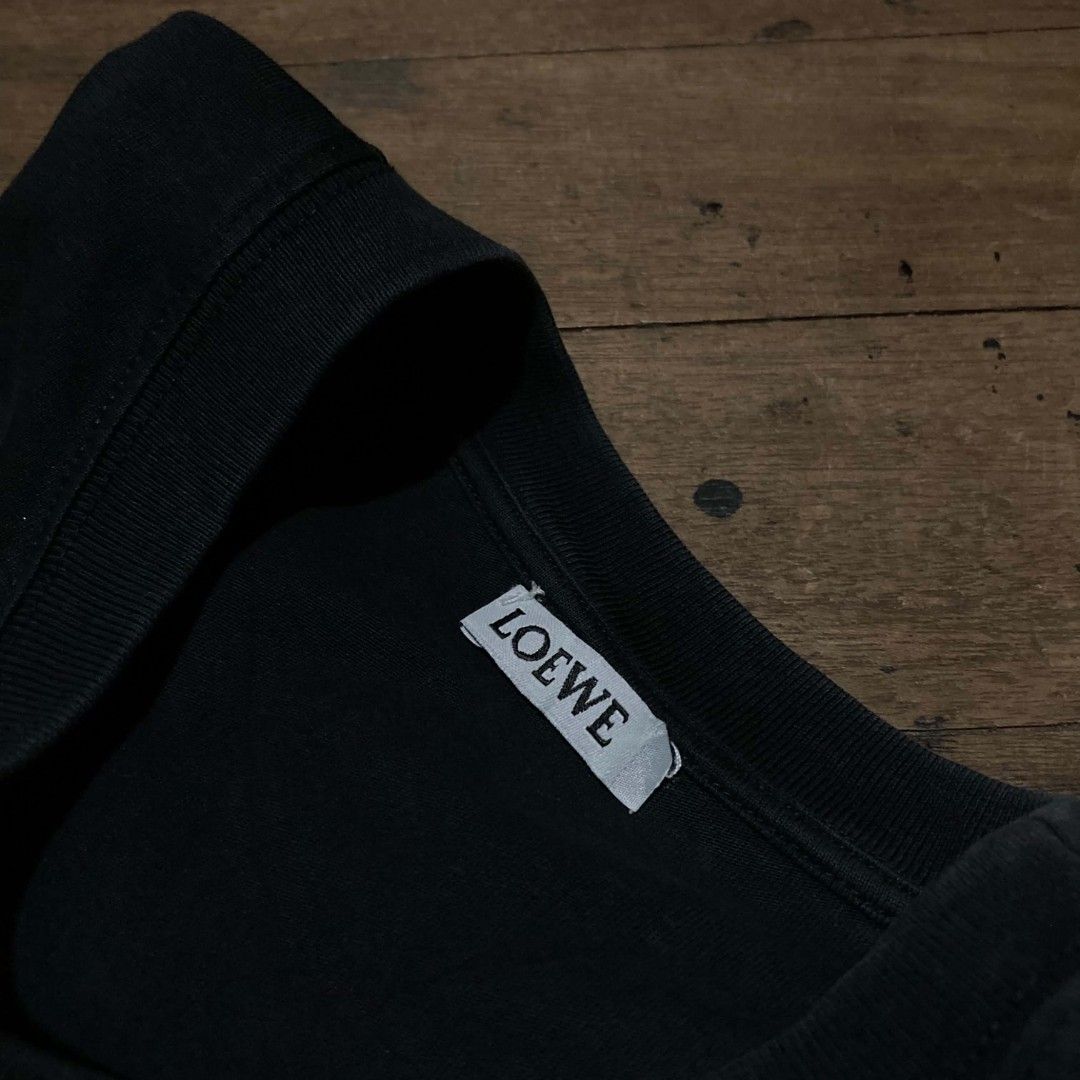 Loewe Black Anagram Tee Shirt Size M (Category: Activewear) located in Manila. Submitted by bravebird_164362 (Listing ID 1470507786, Image 3). Description: - Color: Black with pink raised Anagram logo on chest - Material: 100% Cotton (Made in Portugal) - Size: Medium (tag attached near hem) - Design: Classic crew neck and short sleeves - Condition: Clean fabric with minimal wear - Mode of Payment: Gcash / Bank Transfer - Shipping: Via J&T or LBC 
