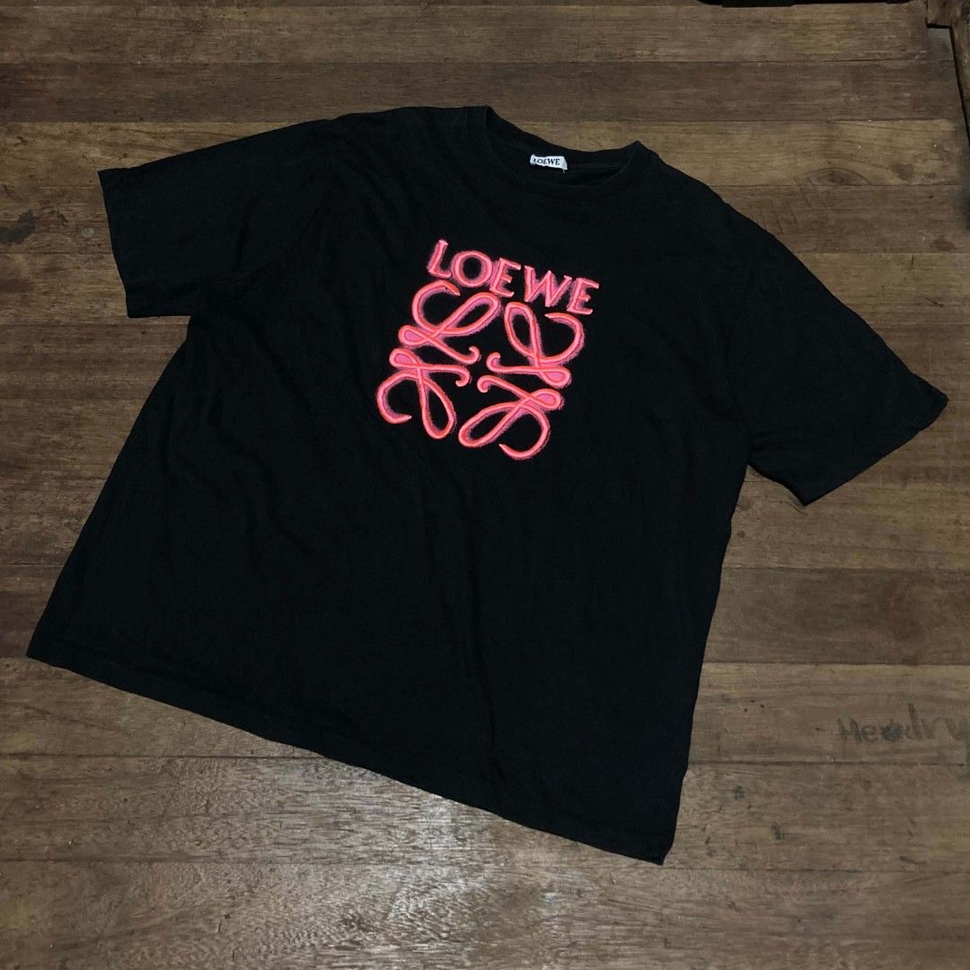 Loewe Black Anagram Tee Shirt Size M (Category: Activewear) located in Manila. Submitted by bravebird_164362 (Listing ID 1470507786, Image 2). Description: - Color: Black with pink raised Anagram logo on chest - Material: 100% Cotton (Made in Portugal) - Size: Medium (tag attached near hem) - Design: Classic crew neck and short sleeves - Condition: Clean fabric with minimal wear - Mode of Payment: Gcash / Bank Transfer - Shipping: Via J&T or LBC 