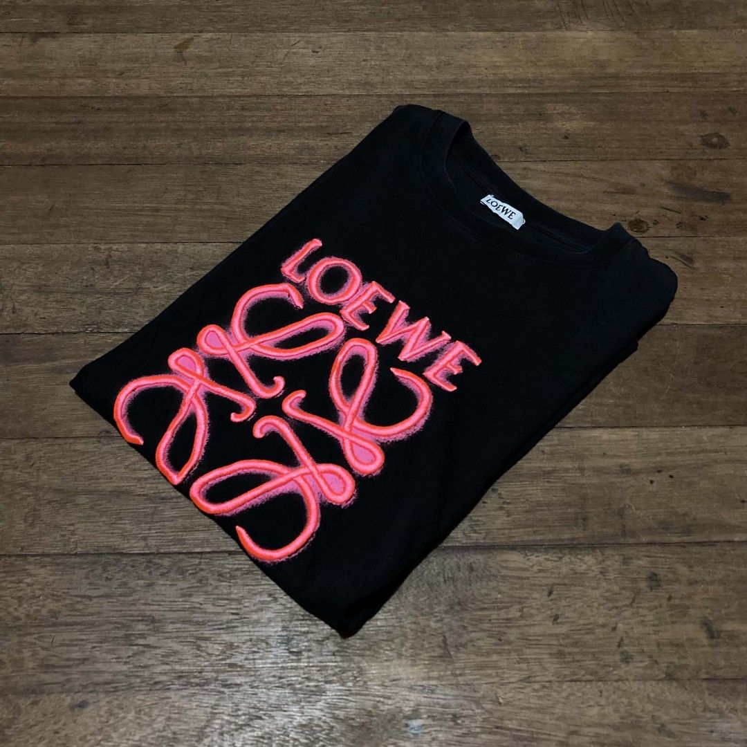 Loewe Black Anagram Tee Shirt Size M (Category: Activewear) located in Manila. Submitted by bravebird_164362 (Listing ID 1470507786, Image 1). Description: - Color: Black with pink raised Anagram logo on chest - Material: 100% Cotton (Made in Portugal) - Size: Medium (tag attached near hem) - Design: Classic crew neck and short sleeves - Condition: Clean fabric with minimal wear - Mode of Payment: Gcash / Bank Transfer - Shipping: Via J&T or LBC 