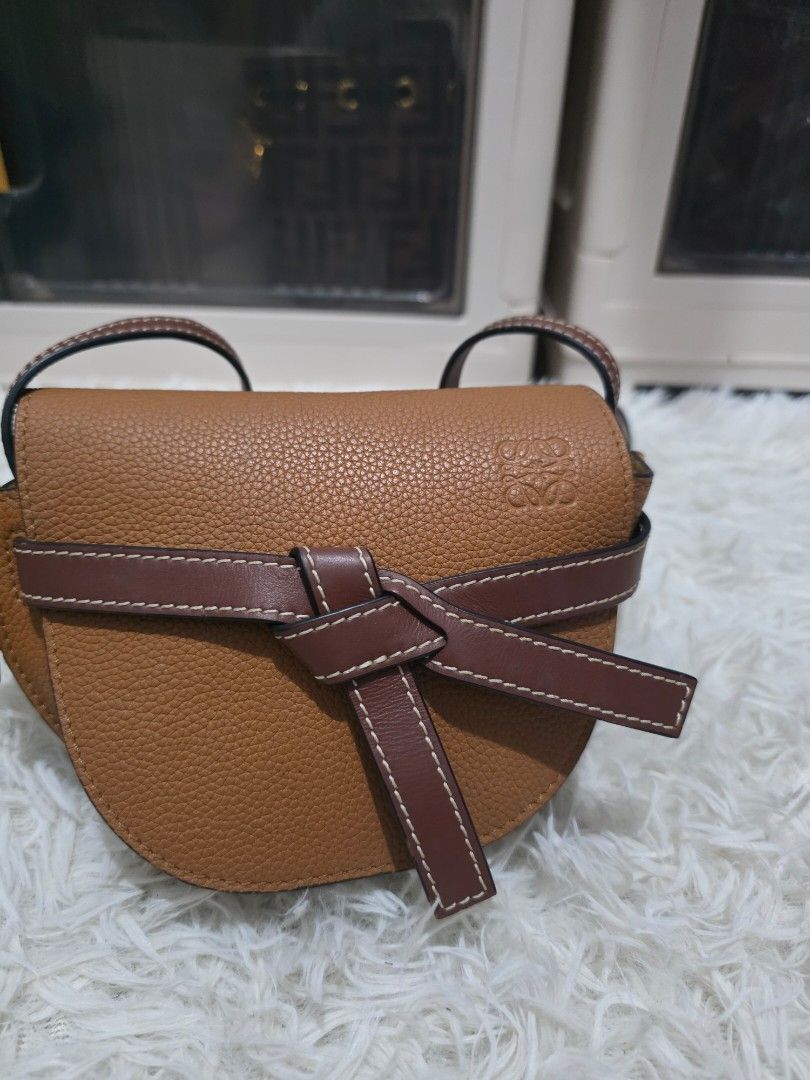 Loewe Gate Small Leather Crossbody Bag Tan (Category: Cross-body Bags) located in Lemery. Submitted by venus23 (Listing ID 1470512323, Image 1). Description: - Material: Tan pebble grain leather with structured saddle shape - Accents: Contrasting dark brown strap detail, front flap knot closure, and gold-tone hardware - Branding & Finish: Embossed logo on top left flap with black edge glazing - Strap: Adjustable thin shoulder strap - Condition: S