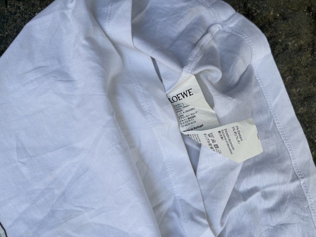 Loewe Graphic Print T-Shirt White (Category: Shirts) located in Manila. Submitted by shanaaa.collects (Listing ID 1470394398, Image 3). Description: - Brand: Loewe - Color: Clean White - Design: Large portrait graphic print on front with bold black branding - Neckline: Ribbed crew neck - Material: Premium cotton blend with elastane for comfortable stretch - Origin: Made in Portugal - Condition: Excellent, comes with full interior brand and care t