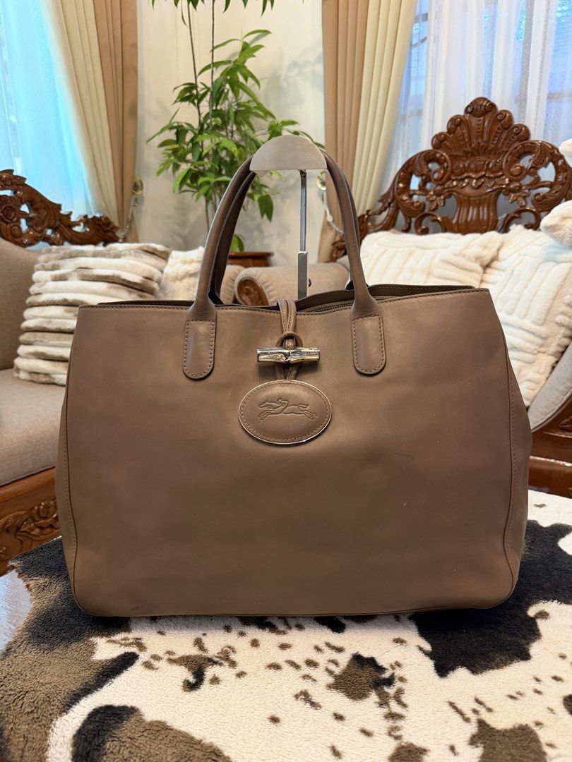 Longchamp Roseau Leather Heritage Bag (Category: Tote Bags) located in Santiago. Submitted by yrellagnoihsaf (Listing ID 1470382497, Image 1). Description: ORIG Longchamp Roseau Heritage leather tote bag in a clay or taupe/beige color, featuring dual rolled handles, silver-tone hardware, an embossed oval logo on the front, and the signature bamboo-accented toggle closure. Normal signs of usage no rips no hole. 🌷.