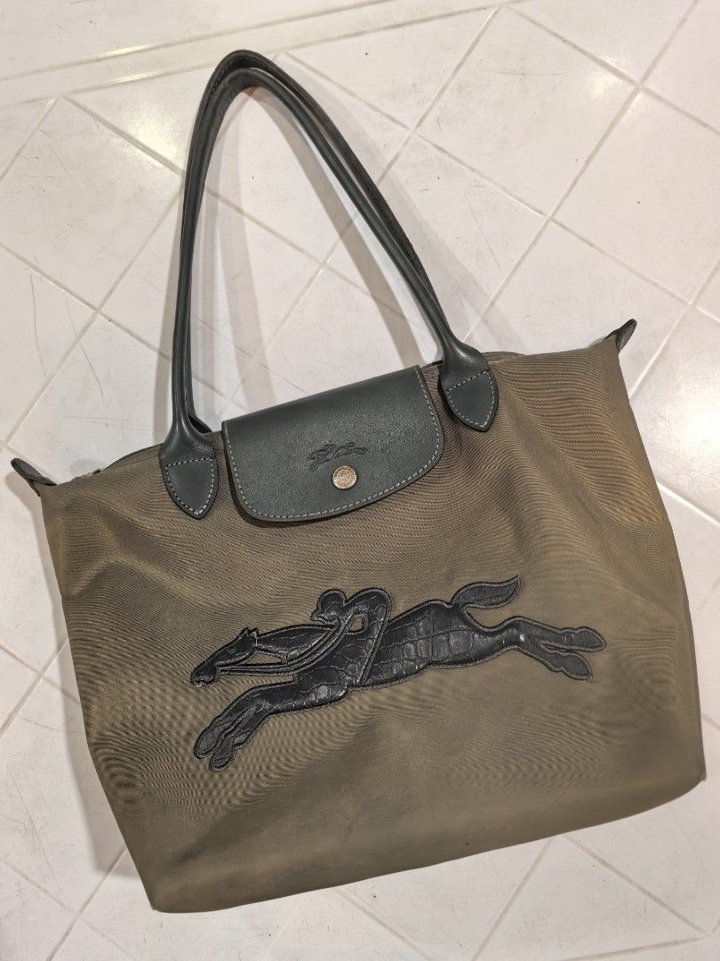 Longchamp Tote Bag (Category: Tote Bags) located in Manila. Submitted by jsu2026 (Listing ID 1470500500, Image 1). Description: - Brand: Longchamp - Material: Durable green nylon with dark grey leather handles and flap - Closure: Zipper top with snap button flap - Details: Large embossed horse logo on the front - Condition: Shows minor signs of wear and light marks on the fabric and base - Style: Great everyday casual tote bag.