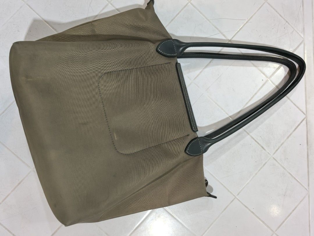 Longchamp Tote Bag (Category: Tote Bags) located in Manila. Submitted by jsu2026 (Listing ID 1470500500, Image 3). Description: - Brand: Longchamp - Material: Durable green nylon with dark grey leather handles and flap - Closure: Zipper top with snap button flap - Details: Large embossed horse logo on the front - Condition: Shows minor signs of wear and light marks on the fabric and base - Style: Great everyday casual tote bag.