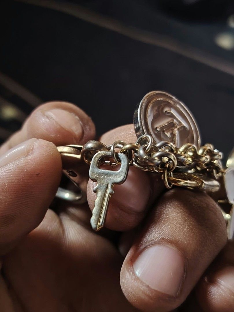Louis Vuitton Bag Charm Keychain (Category: Charms) located in Baguio. Submitted by tabuzomaria1422 (Listing ID 1470463094, Image 2). Description: Louis Vuitton keyring and bag charm. Gold-tone hardware with engraved logo on the clasp. Includes dangling charms: a pink enamel LV circle medallion, brown enamel Monogram flower charms, a miniature padlock, and a key. Shows some tarnishing and wear on the metal parts..
