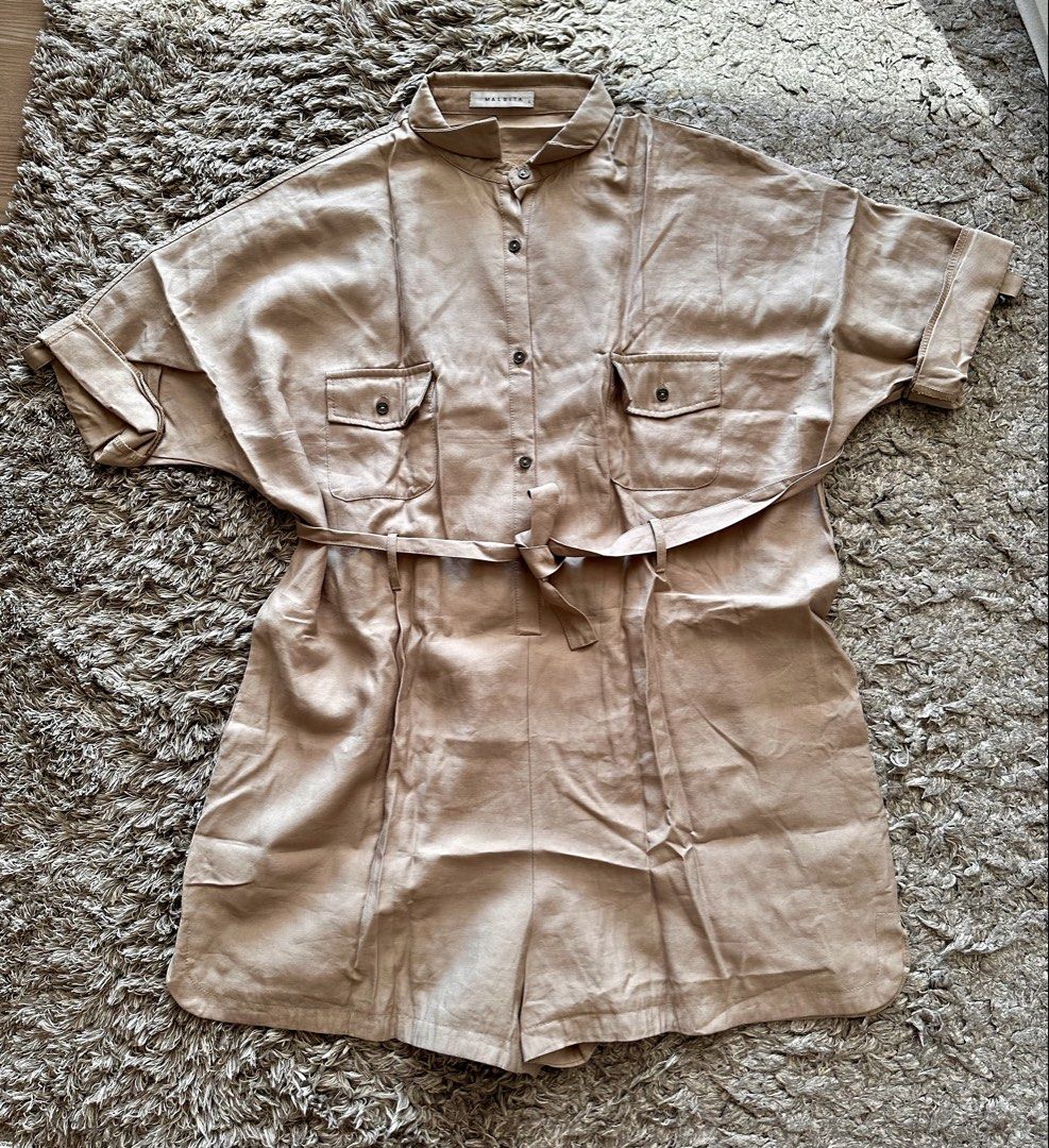 Maldita Tan Short Sleeve Button-Up Romper Size L (Category: Rompers) located in Quezon City. Submitted by k_prelovedpieces (Listing ID 1470393765, Image 1). Description: - Brand: Maldita - Size: Large (L) - Color: Versatile tan/neutral - Design: Button-up front, mandarin collar, short sleeves, and built-in waist tie belt - Pockets: Two chest pockets with button flaps - Fit: Relaxed fit shorts attached - Material: Smooth, comfortable fabric - Styl