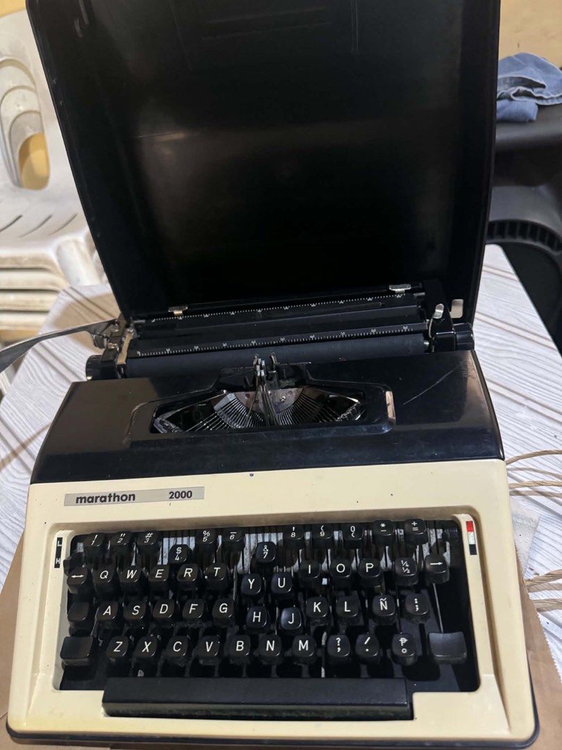 Marathon 2000 Portable Typewriter with Case (Category: Stationery & School Supplies) located in Malolos. Submitted by afsillano (Listing ID 1470432827, Image 2). Description: - Model: Marathon 2000 typewriter - Color: Classic black and cream - Layout: Standard QWERTY keyboard with full number and symbol rows - Mechanism: Standard manual typing with visible typebars - Protection: Integrated hard lid case that covers the paper table and carriage - 