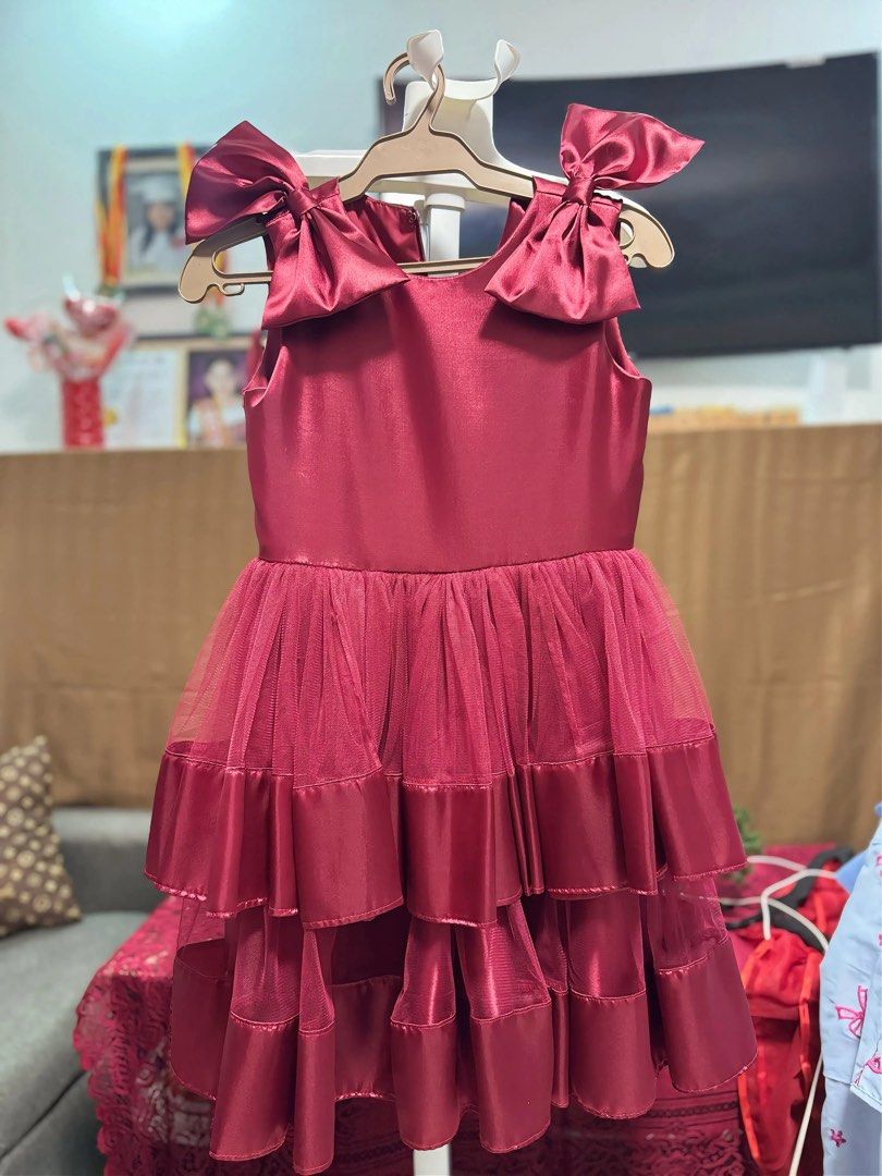 Maroon tiered dress with shoulder bows (Category: Dresses) located in Mabalacat. Submitted by charm222 (Listing ID 1470501760, Image 1). Description: - Color: Deep maroon - Style: Sleeveless midi dress with a round neckline - Design details: Eye-catching big satin bows on the shoulders - Skirt: Multiple layered tiers combining shiny satin and sheer mesh fabric - Condition: Clean and ready to wear - Perfect for parties, formal events, and date nig