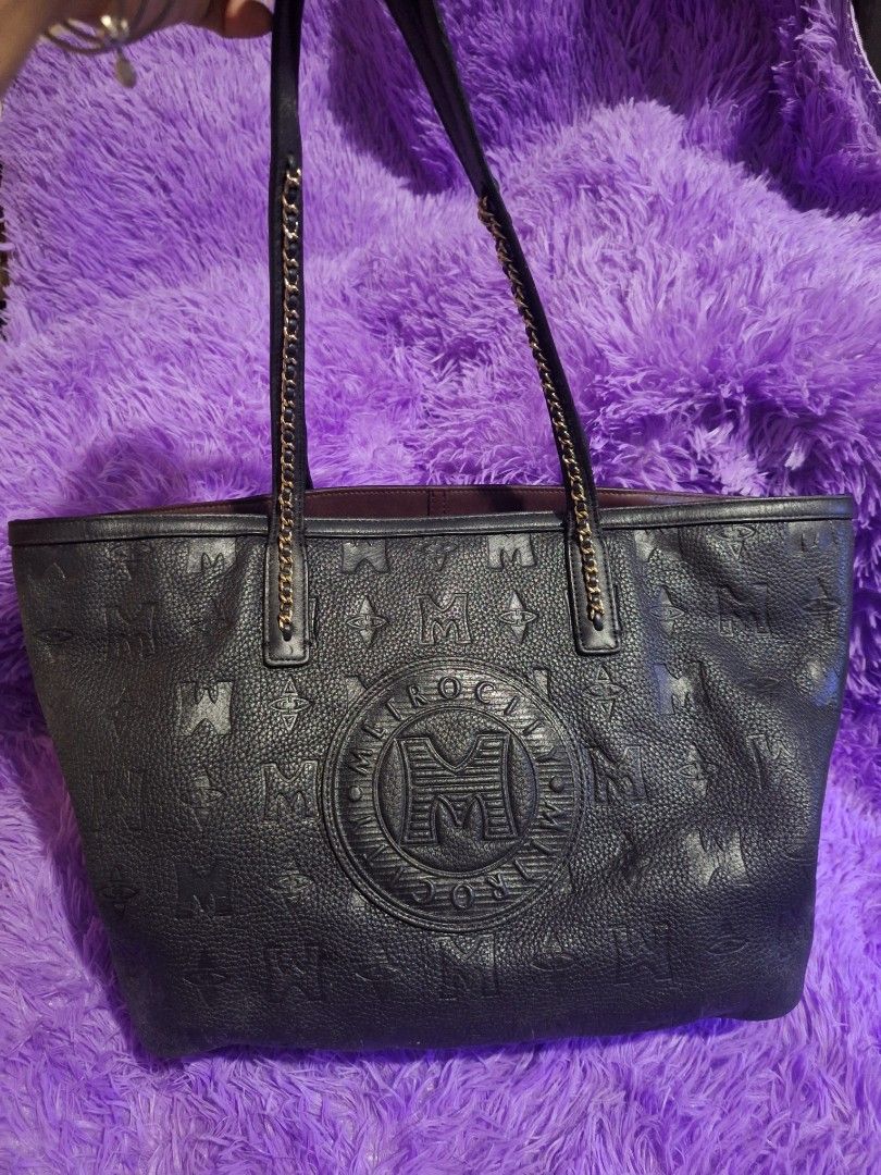 Metrocity Black Leather Tote Bag (Category: Tote Bags) located in Quezon City. Submitted by cloudymay (Listing ID 1470430417, Image 1). Description: - Brand: Metrocity - Material: Premium black leather with debossed monogram print - Hardware: Gold-tone accents and medallion logo - Straps: Comfortable double shoulder straps combining leather and gold chain links - Interior: Spacious with a rich deep purple lining - Structure: Flat structured base 
