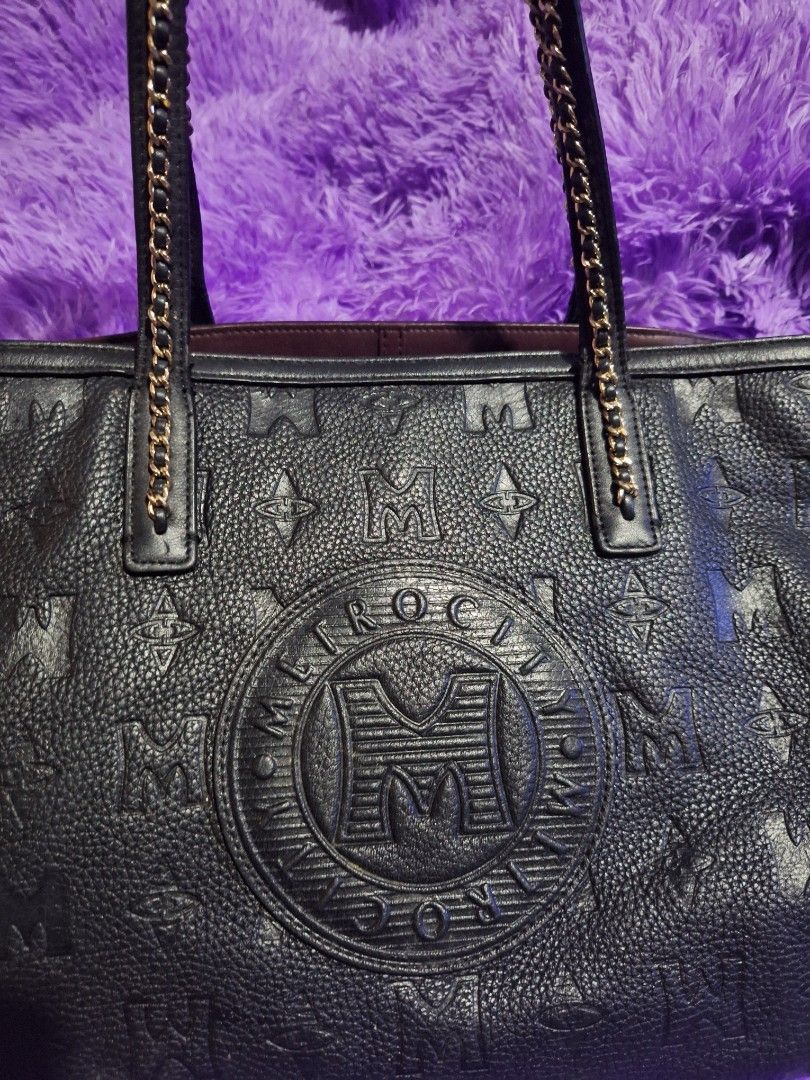 Metrocity Black Leather Tote Bag (Category: Tote Bags) located in Quezon City. Submitted by cloudymay (Listing ID 1470430417, Image 2). Description: - Brand: Metrocity - Material: Premium black leather with debossed monogram print - Hardware: Gold-tone accents and medallion logo - Straps: Comfortable double shoulder straps combining leather and gold chain links - Interior: Spacious with a rich deep purple lining - Structure: Flat structured base 