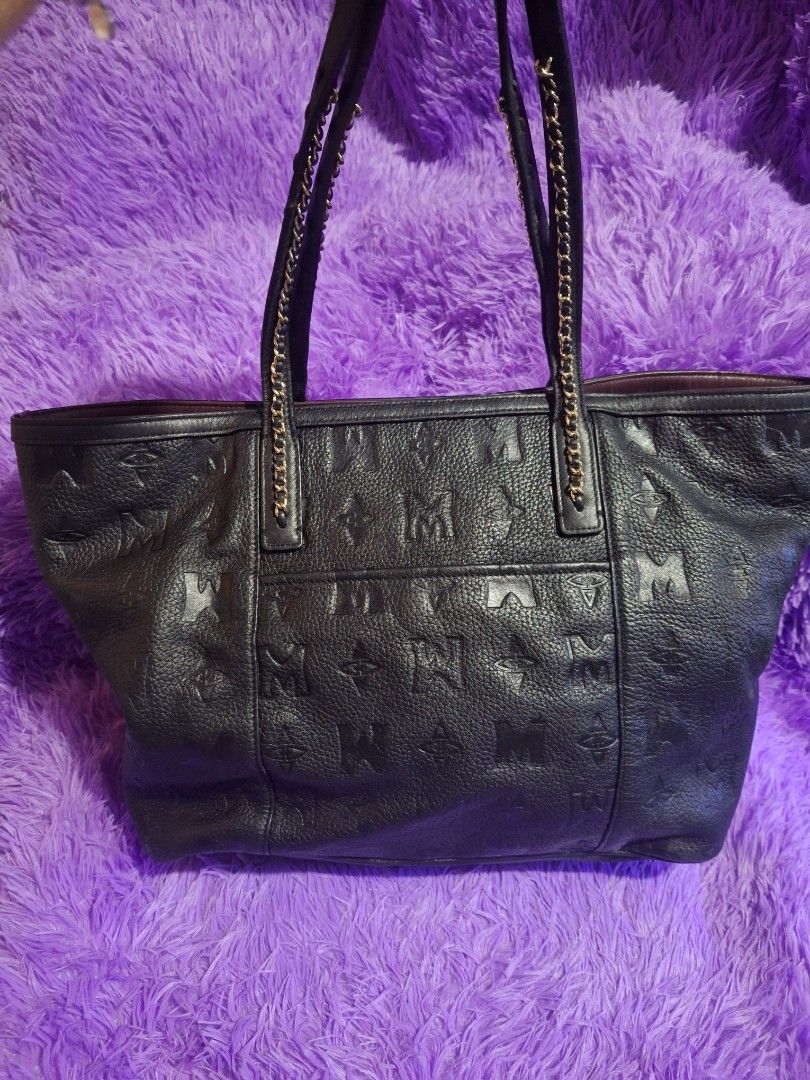 Metrocity Black Leather Tote Bag (Category: Tote Bags) located in Quezon City. Submitted by cloudymay (Listing ID 1470430417, Image 3). Description: - Brand: Metrocity - Material: Premium black leather with debossed monogram print - Hardware: Gold-tone accents and medallion logo - Straps: Comfortable double shoulder straps combining leather and gold chain links - Interior: Spacious with a rich deep purple lining - Structure: Flat structured base 