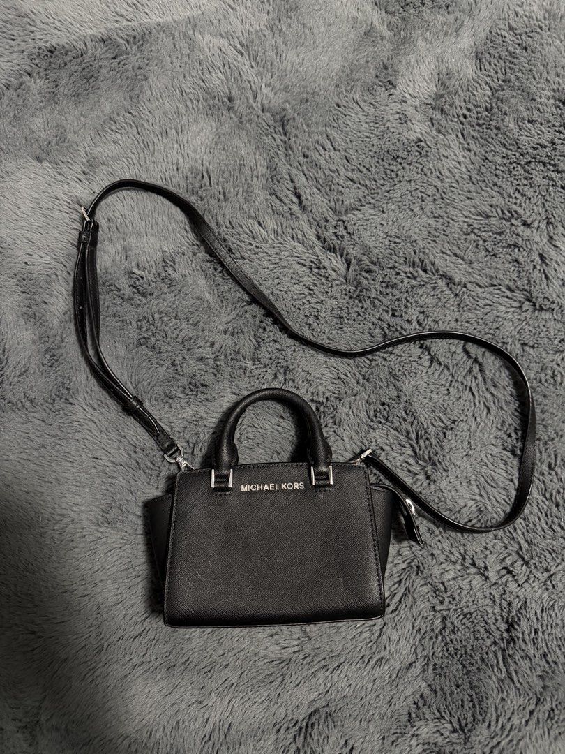 Michael Kors Black Mini Crossbody Bag (Category: Cross-body Bags) located in Koronadal. Submitted by chaifinds (Listing ID 1470519862, Image 1). Description: Black leather Michael Kors mini crossbody bag with silver-toned hardware. Dual top handles plus an adjustable, removable strap. Zip top closure opens to a fabric-lined interior with branding. Compact size for daily essentials, keys, and phone. Clean structure, firm material..