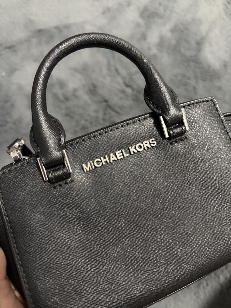 Michael Kors Black Mini Crossbody Bag (Category: Cross-body Bags) located in Koronadal. Submitted by chaifinds (Listing ID 1470519862, Image 2). Description: Black leather Michael Kors mini crossbody bag with silver-toned hardware. Dual top handles plus an adjustable, removable strap. Zip top closure opens to a fabric-lined interior with branding. Compact size for daily essentials, keys, and phone. Clean structure, firm material..