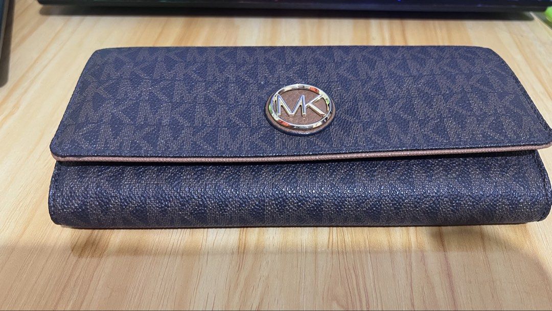 Michael Kors Brown Monogram Logo Trifold Wallet (Category: Luxury Bags & Wallets) located in Caloocan City. Submitted by yhanggirl (Listing ID 1470454820, Image 1). Description: - Brand: Michael Kors - Design: Brown signature monogram print with brown leather trim - Hardware: Two-tone silver and gold MK logo medallion on front flap - Interior: Multiple card slots and spacious cash compartments - Condition: Clean exterior and tidy edges - Use: Per