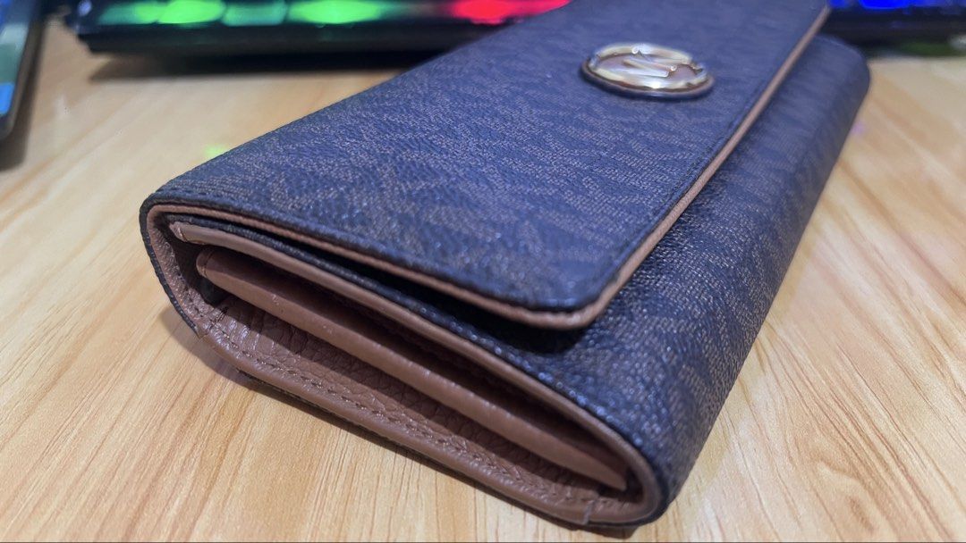Michael Kors Brown Monogram Logo Trifold Wallet (Category: Luxury Bags & Wallets) located in Caloocan City. Submitted by yhanggirl (Listing ID 1470454820, Image 2). Description: - Brand: Michael Kors - Design: Brown signature monogram print with brown leather trim - Hardware: Two-tone silver and gold MK logo medallion on front flap - Interior: Multiple card slots and spacious cash compartments - Condition: Clean exterior and tidy edges - Use: Per