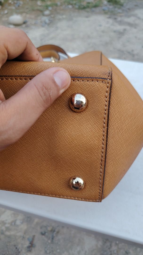 Michael Kors Brown Saffiano Leather Handbag (Category: Luxury Bags & Wallets) located in Bauang. Submitted by wornskript (Listing ID 1470496111, Image 3). Description: MICHAEL Michael Kors Brown Saffiano Leather Tote Bag 🤎👜 ✨ Thrifted Item 👜 Medium Cynthia Tote 🎨 Brown ⚠️ Issue: The MK medallion/logo pendant is missing. ⚠️ Issue:Please refer to the last two photos for details. 💬 Price is based on the item's current condition and overall qual
