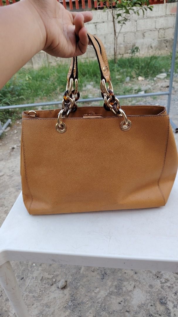 Michael Kors Brown Saffiano Leather Handbag (Category: Luxury Bags & Wallets) located in Bauang. Submitted by wornskript (Listing ID 1470496111, Image 2). Description: MICHAEL Michael Kors Brown Saffiano Leather Tote Bag 🤎👜 ✨ Thrifted Item 👜 Medium Cynthia Tote 🎨 Brown ⚠️ Issue: The MK medallion/logo pendant is missing. ⚠️ Issue:Please refer to the last two photos for details. 💬 Price is based on the item's current condition and overall qual