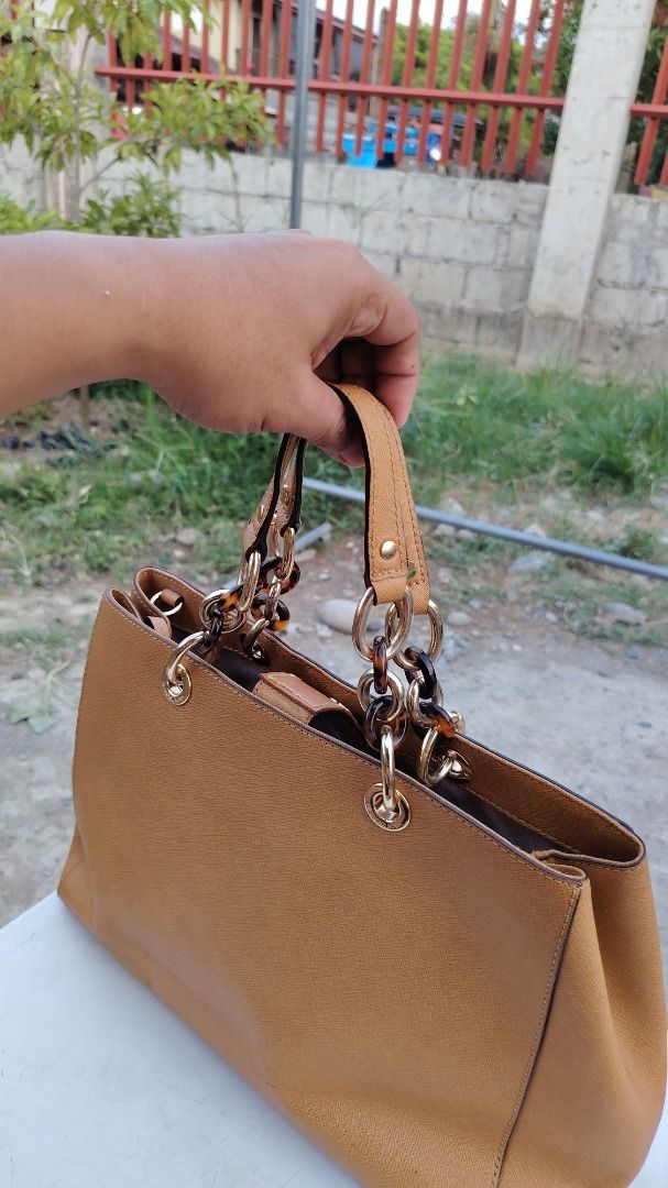 Michael Kors Brown Saffiano Leather Handbag (Category: Luxury Bags & Wallets) located in Bauang. Submitted by wornskript (Listing ID 1470496111, Image 1). Description: MICHAEL Michael Kors Brown Saffiano Leather Tote Bag 🤎👜 ✨ Thrifted Item 👜 Medium Cynthia Tote 🎨 Brown ⚠️ Issue: The MK medallion/logo pendant is missing. ⚠️ Issue:Please refer to the last two photos for details. 💬 Price is based on the item's current condition and overall qual