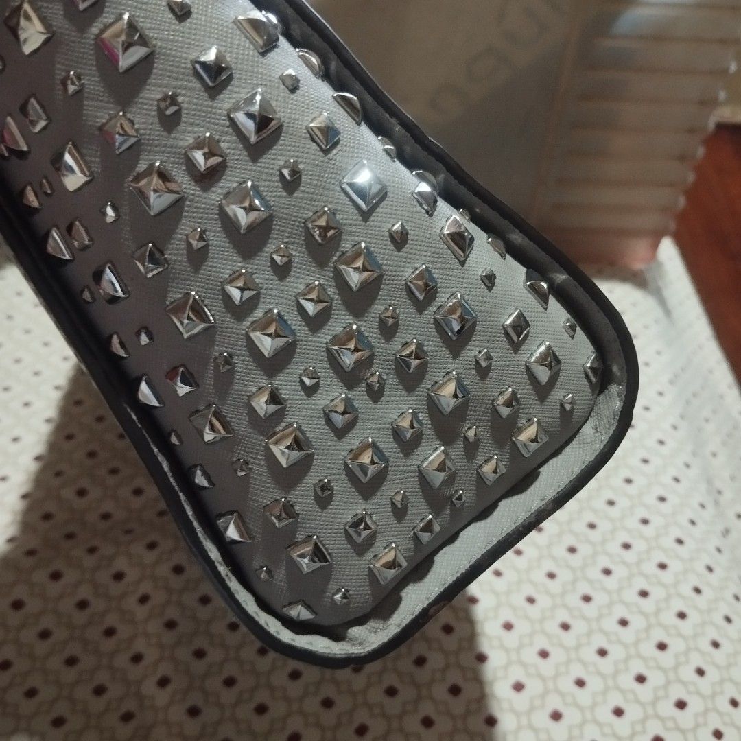 Michael Kors Grey Studded Crossbody Bag (Category: Cross-body Bags) located in Manila. Submitted by lene48 (Listing ID 1470503428, Image 3). Description: Light grey Michael Kors handbag. Saffiano leather material. Silver tone hardware and metallic stud details along the sides. Zippered top closure. Interior features fabric lining, slip pockets, and a zippered pocket. Adjustable matching shoulder strap included inside..
