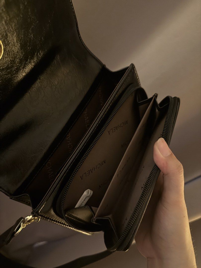 MICHAELA Black Crossbody Bag with Adjustable Strap (Category: Cross-body Bags) located in Mandaluyong City. Submitted by k_closet00 (Listing ID 1470454132, Image 2). Description: - Brand: MICHAELA - Color: Classic Black - Style: Sleek crossbody bag with flap closure and gold lettering logo - Strap: Adjustable fabric shoulder strap - Interior: Clean fabric lining with printed branding, multiple compartments, and zippered sections - In good conditi