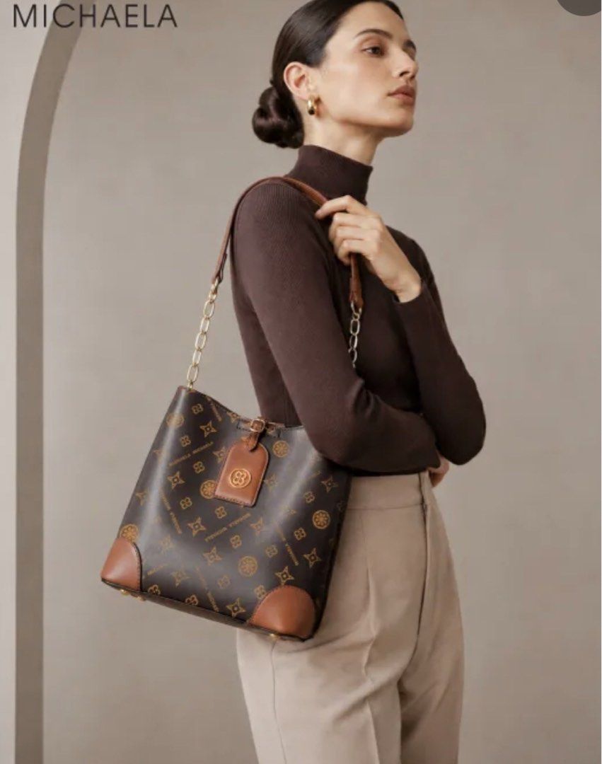 MICHAELA Monogram Bucket Bag Brown Shoulder Bag (Category: Luxury Bags & Wallets) located in Calapan. Submitted by shakalak (Listing ID 1470410815, Image 1). Description: - Brand: MICHAELA ( H 8”/L 9/W 4.5 - Style: Bucket bag in classic brown monogram print with chic tan leather trim and gold-tone hardware - Closure: Open top design with a secure strap closure - Straps: Includes a stylish chain-link shoulder strap and a detachable, adjustable lon