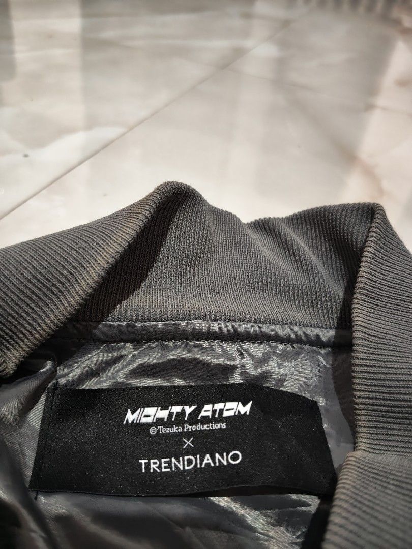 Mighty Atom x Trendiano Astro Boy Bomber Jacket (Category: Coats, Jackets and Outerwear) located in Rizal, Mindoro Occidental. Submitted by finding_ukaygems5103 (Listing ID 1470528841, Image 2). Description: - Brand: Mighty Atom x Trendiano - Color: Dark grey - Design: All-over Astro Boy face graphic print with 'A' letter accents - Closure: Full zip with custom Astro Boy zipper pull - Details: Multiple front and sleeve utility pockets with D-ring