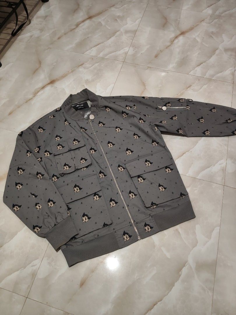 Mighty Atom x Trendiano Astro Boy Bomber Jacket (Category: Coats, Jackets and Outerwear) located in Rizal, Mindoro Occidental. Submitted by finding_ukaygems5103 (Listing ID 1470528841, Image 1). Description: - Brand: Mighty Atom x Trendiano - Color: Dark grey - Design: All-over Astro Boy face graphic print with 'A' letter accents - Closure: Full zip with custom Astro Boy zipper pull - Details: Multiple front and sleeve utility pockets with D-ring