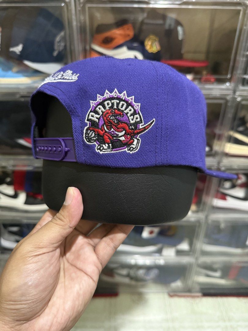 (Wool) Mitchell & Ness Toronto Raptors Snapback Cap Purple (Category: Caps & Hats) located in Manila. Submitted by batoy8814895 (Listing ID 1470434279, Image 2). Description: - Brand: Mitchell & Ness - Team: Toronto Raptors (Throwback Purple Colorway) - Logos: Classic script on front, iconic dinosaur on the side - Fit: Adjustable plastic snap closure - Brim: Flat brim with original authenticity sticker attached - Condition: Brand new / Excellent.