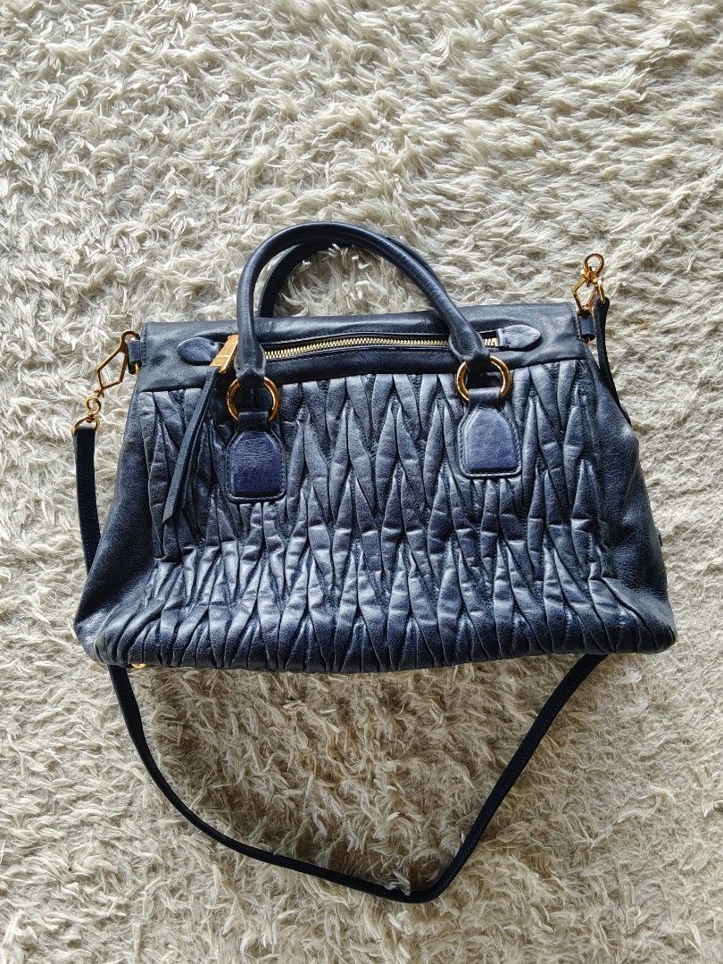 MIU MIU MATELASSE LEATHER SATCHEL (Category: Luxury Bags & Wallets) located in Valencia. Submitted by coolwolf_27a64f (Listing ID 1470366800, Image 2). Description: Authentic Miu Miu Matelassé Leather Satchel Bag in Navy Blue 🔵 ✨ Features the iconic gathered matelassé quilting, dual structured top handles, and a detachable crossbody strap for versatile styling. Complemented by striking gold-tone hardware and the classic front logo lettering. Per