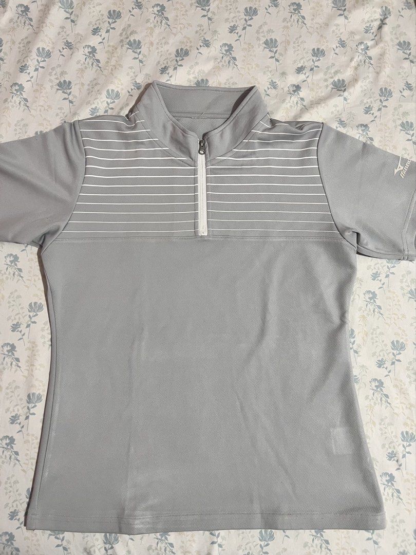 Mizuno Gray Half-Zip Striped Athletic Shirt (Category: Tshirts & Polo Shirts ) located in Imus. Submitted by colesj (Listing ID 1470461094, Image 2). Description: - Brand: Mizuno - Color: Gray with white horizontal chest stripes - Features: Half-zip collar, short sleeves with printed logo on left sleeve - Material: 100% polyester (athletic, quick-dry) - Fits Small to Medium ⚠️ Has a small hole on the sleeve/arm area (see photos) Selling because I