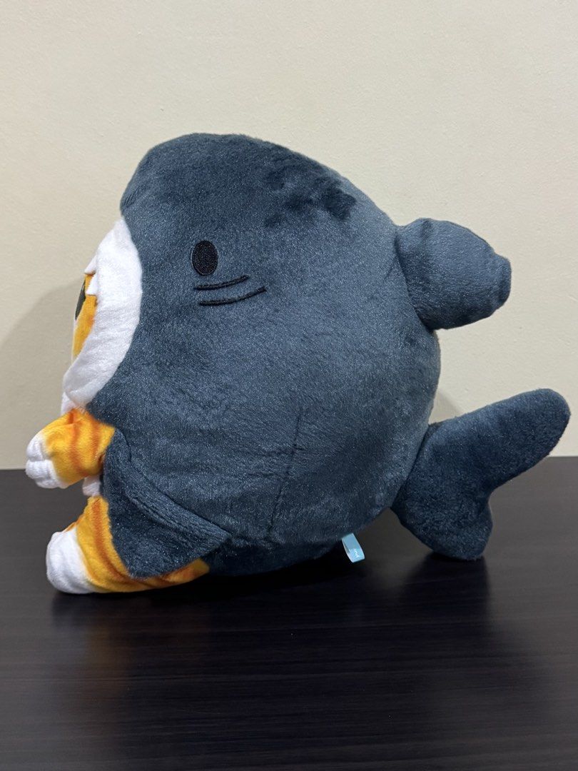 Mofusand Shark Cat Plush Stuffed Toy (Category: Plushies & Soft Toys) located in Cainta. Submitted by mayhroeen (Listing ID 1470538213, Image 2). Description: - Adorable orange tabby cat wearing a dark gray shark costume - Features white teeth framing the face and tiny embroidered paws - Made with soft fabric and fluffy filling for a cuddly feel - Includes a light blue brand tag stitched on the side - Clean condition, no stains or loose threads -