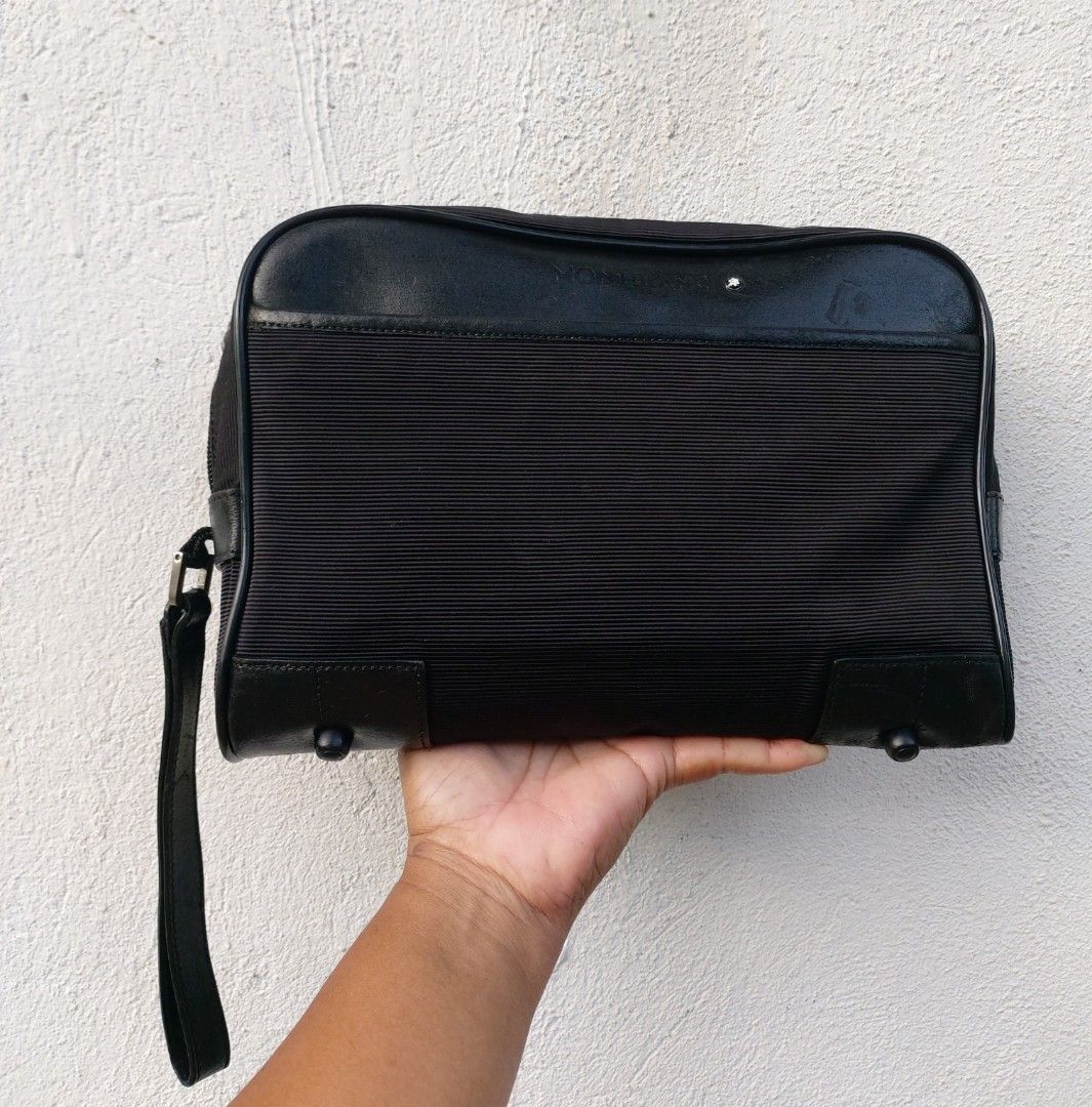 Montblanc Black Clutch Bag (Category: Luxury Bags & Wallets) located in Lapu Lapu. Submitted by agnesapm_29813 (Listing ID 1470488699, Image 2). Description: - Brand: Montblanc - Color: Classic Black - Material: Premium ribbed fabric with genuine leather trim - Portability: Convenient side wrist strap - Protection: Metal feet on the bottom base - Interior: Roomy main compartment for all grooming and travel essentials - Measurements: width-10.5 in