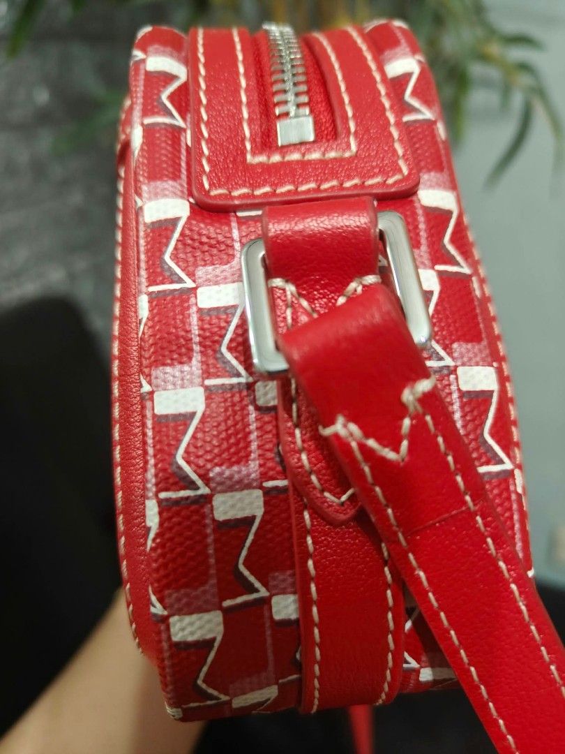 Moynat Red Patterned Crossbody Bag (Category: Luxury Bags & Wallets) located in Bay. Submitted by silverhorse-59c851 (Listing ID 1470557264, Image 3). Description: - Brand: Moynat Crossbody Bag - Color/Pattern: Red with white and pink signature monogram - Closure: Zip-top main compartment with exterior flap pocket - Strap: Red leather shoulder strap with silver-tone hardware - Interior: Cream fabric lining with a convenient slip pocket - Style: C