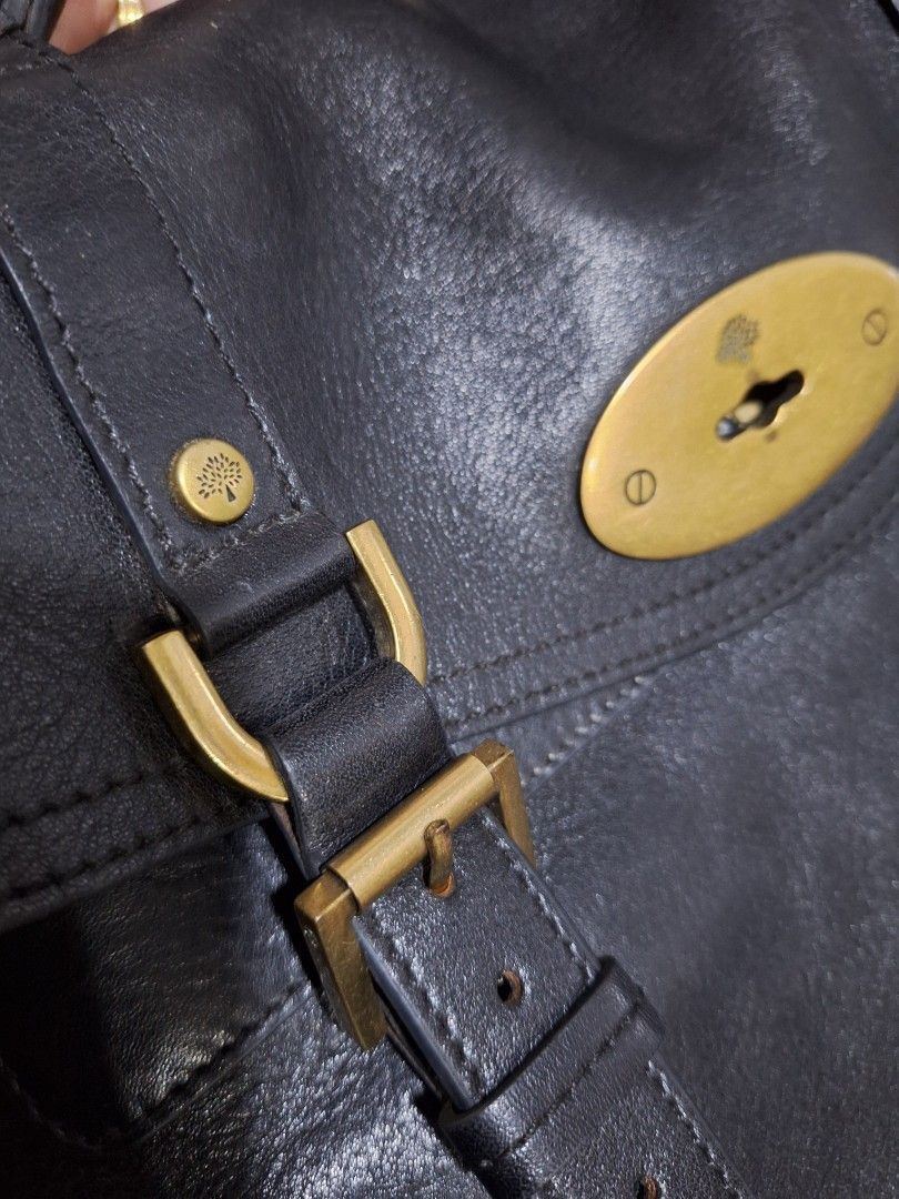 Mulberry Black Leather Shoulder Bag (Category: Luxury Bags & Wallets) located in Quezon City. Submitted by cloudymay (Listing ID 1470552032, Image 2). Description: Authentic Black textured leather handbag by Mulberry. Brass hardware including dual buckle straps across the front and central turn-lock closure. Braided top handle plus shoulder strap. Olive green fabric lining featuring Mulberry tree motif throughout. Interior zip pocket and slip com