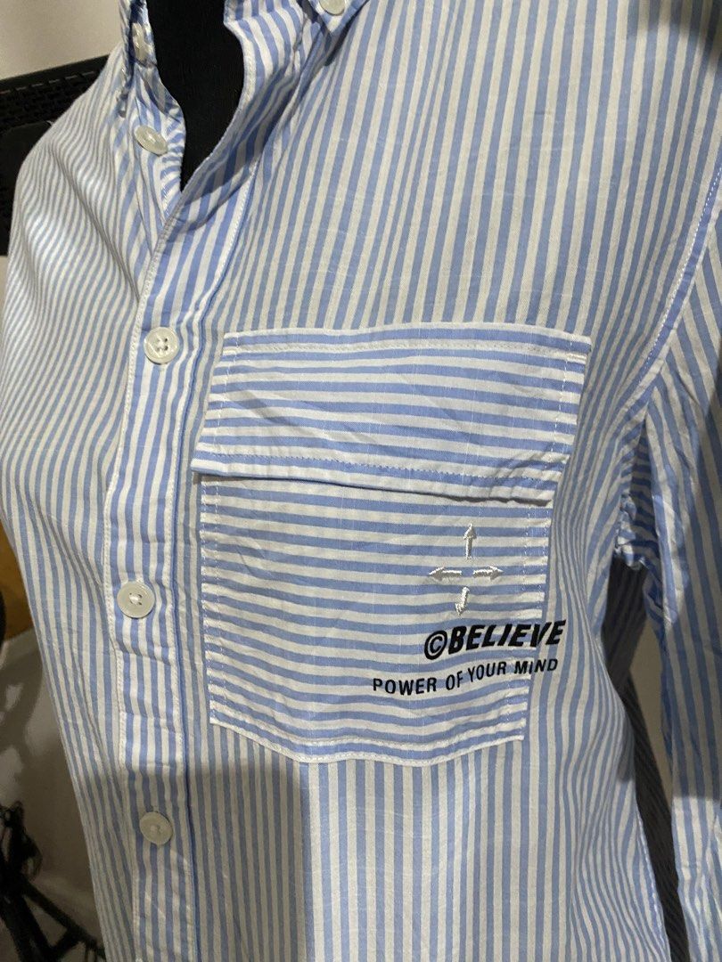 Myth Blue White Striped Button Down Shirt (Category: Tshirts & Polo Shirts ) located in Manila. Submitted by mpt99876 (Listing ID 1470496596, Image 2). Description: - Brand: Myth - Design: Light blue and white vertical stripes - Details: Button collar, chest pocket with 'believe power of your mind' graphic print, and white label tag near the hem - Sleeves: Three-quarter sleeves with convenient button tabs - Style: Versatile casual piece, perfect 