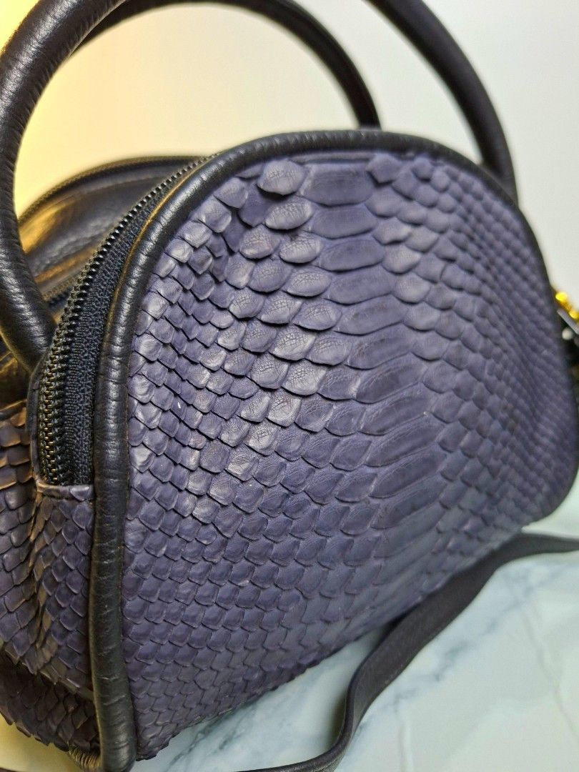 Navy Python Skin Leather Handbag with Strap (Category: Luxury Bags & Wallets) located in Pasay City. Submitted by onick_79 (Listing ID 1470404003, Image 2). Description: - Navy blue python skin texture with smooth black leather trim - Elegant gold-tone hardware and detachable shoulder strap - Dual top zipper closure with secure black pulls - Compact dome shape that stands upright on its own - Versatile design, ideal for both everyday wear and spe
