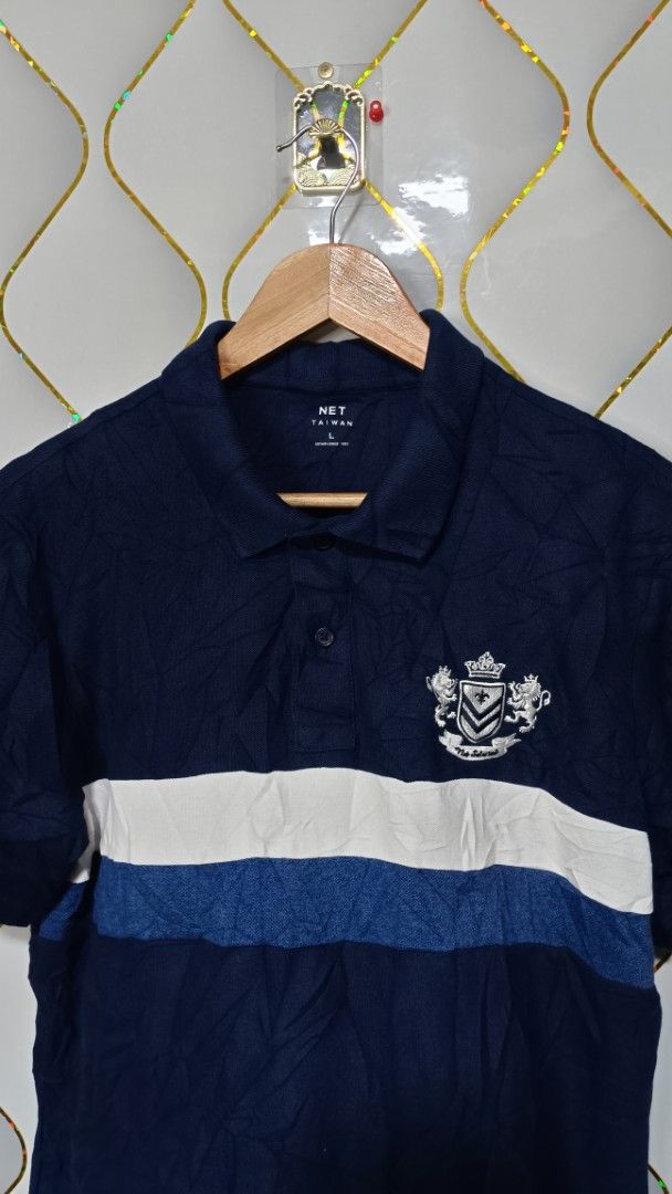 NET Taiwan Blue Polo Shirt (Category: Tshirts & Polo Shirts ) located in Manila. Submitted by zariyah.1986 (Listing ID 1470448505, Image 2). Description: - Brand: NET Taiwan - Color: Navy blue with contrasting white and blue chest stripes - Size: L(21 Inches27 length) - Details: Embroidered crest emblem on left chest, button placket collar - Material: Cotton and polyester blend - Origin: Made in Vietnam.