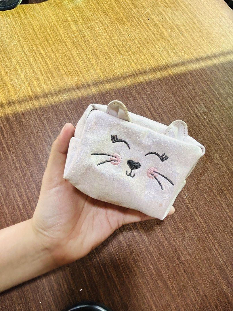 New Look Cat Face Makeup Pouch (Category: Purses & Pouches) located in Manila. Submitted by starbalesukandjapansurplus (Listing ID 1470555441, Image 1). Description: - Brand: New Look - Design: Sparkly iridescent finish with embroidered sleepy eyes, pink cheeks, and 3D cat ears - Hardware: Rose gold zipper closure - Interior: Pink fabric lining with brand tags attached - Condition: Clean interior and exterior - Size: Compact for daily essentials 